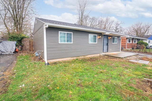 single story home featuring a shingled roof, fence, and a front yard