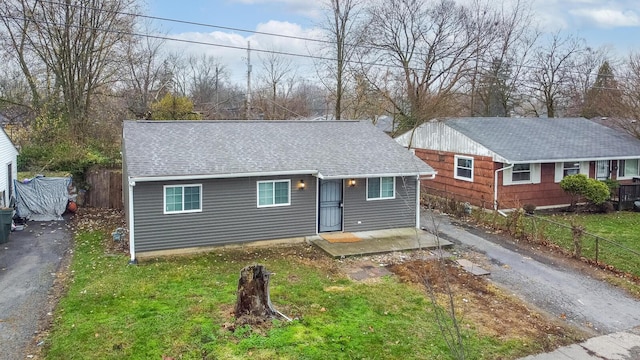 ranch-style house with aphalt driveway, roof with shingles, and fence