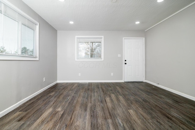 spare room with dark wood-style floors, a textured ceiling, recessed lighting, and baseboards