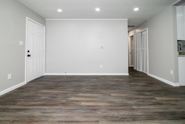 spare room featuring dark wood-style floors, recessed lighting, and baseboards