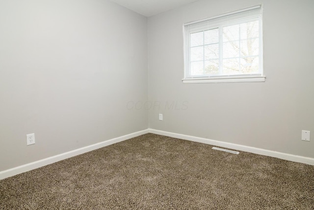 carpeted spare room featuring visible vents and baseboards