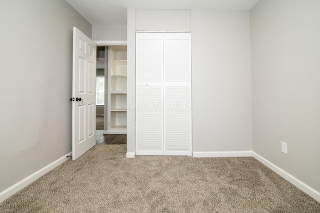 unfurnished bedroom featuring a closet, baseboards, and carpet flooring