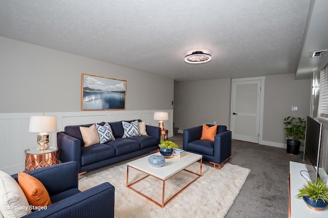 living area featuring a textured ceiling, a wainscoted wall, carpet flooring, and visible vents