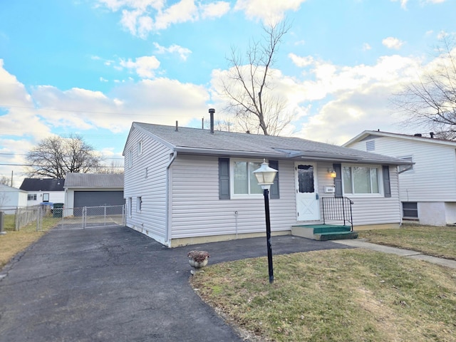 view of front of property with a front yard, a detached garage, fence, and an outbuilding