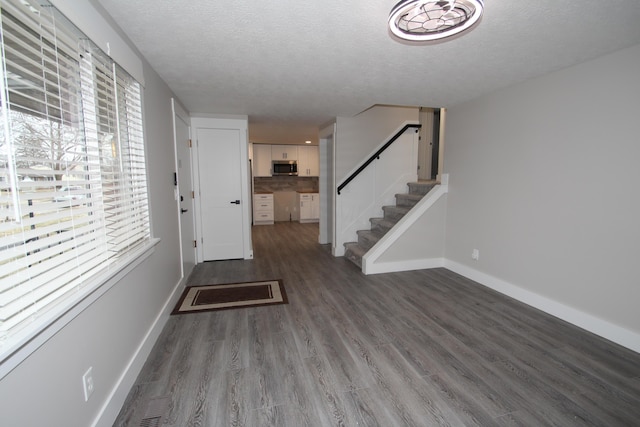 foyer with a textured ceiling, stairway, wood finished floors, and baseboards