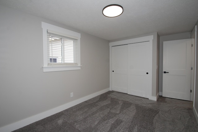 unfurnished bedroom with a closet, a textured ceiling, baseboards, and carpet flooring