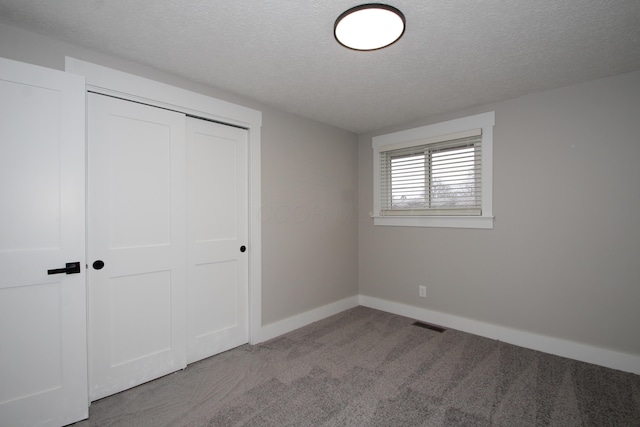 unfurnished bedroom featuring a closet, visible vents, carpet flooring, a textured ceiling, and baseboards