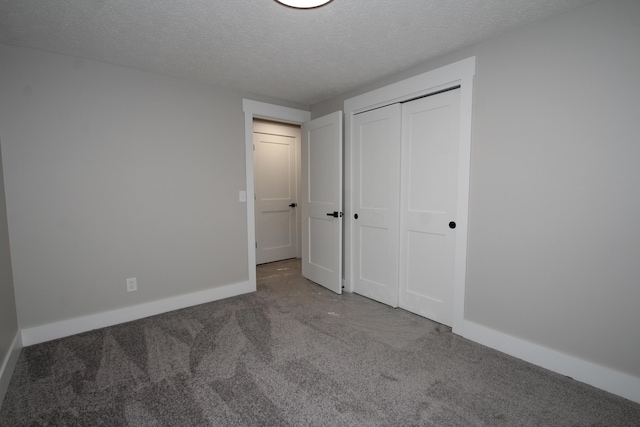 unfurnished bedroom with carpet, a closet, a textured ceiling, and baseboards