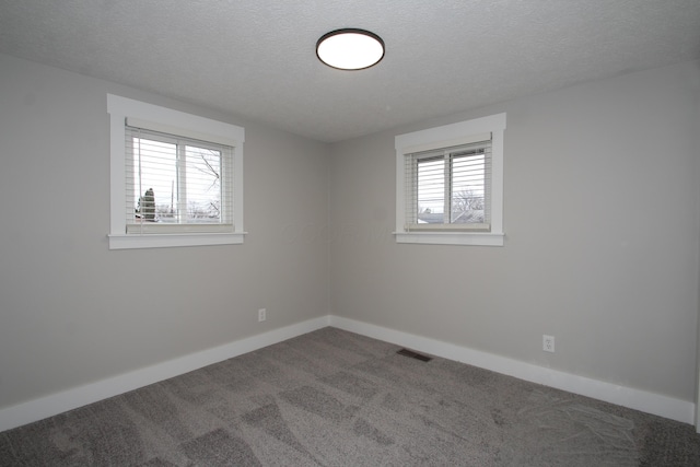 carpeted spare room with a textured ceiling, visible vents, and baseboards