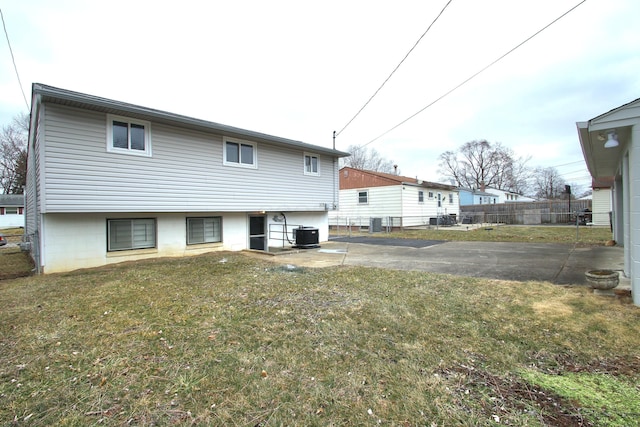 rear view of property featuring a lawn, fence, and central air condition unit