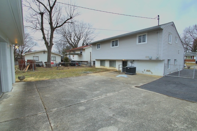 back of house featuring driveway, central AC unit, and fence