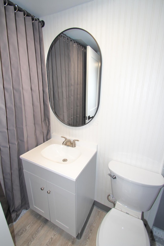 bathroom with toilet, wood finished floors, and vanity