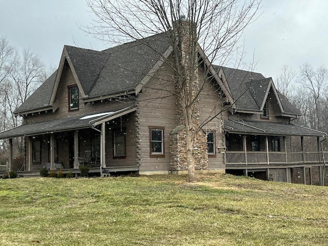 exterior space with a shingled roof, covered porch, a yard, and a chimney