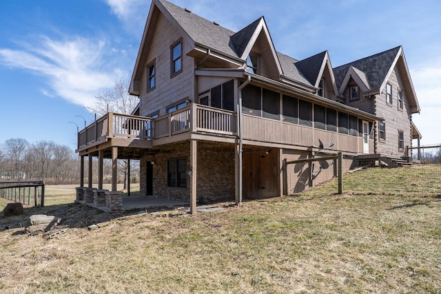 view of property exterior with a patio, a sunroom, stone siding, a yard, and a wooden deck