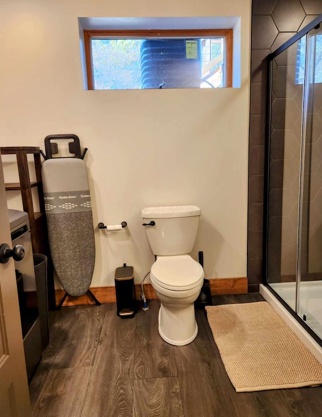 full bathroom featuring a stall shower, baseboards, toilet, and wood finished floors