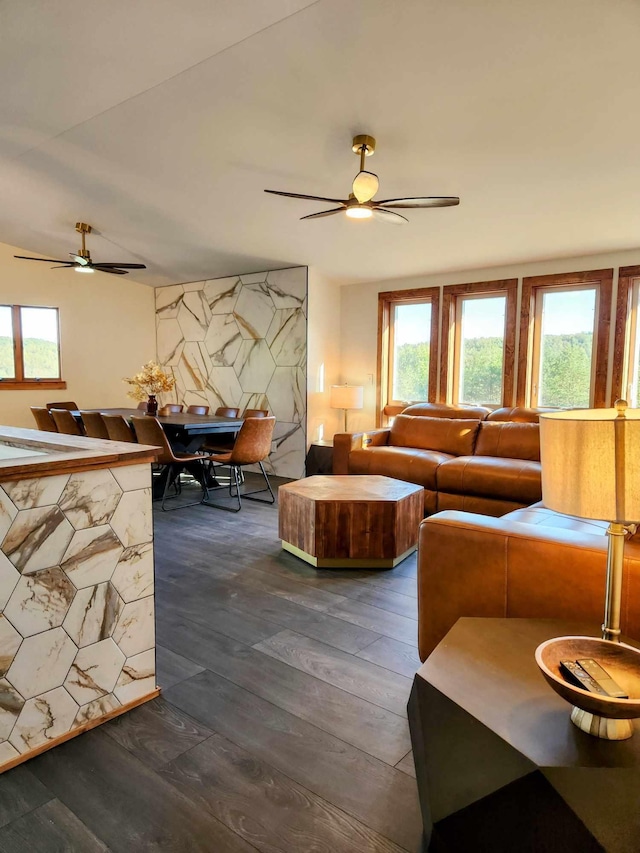 living room featuring an accent wall, dark wood finished floors, and a ceiling fan