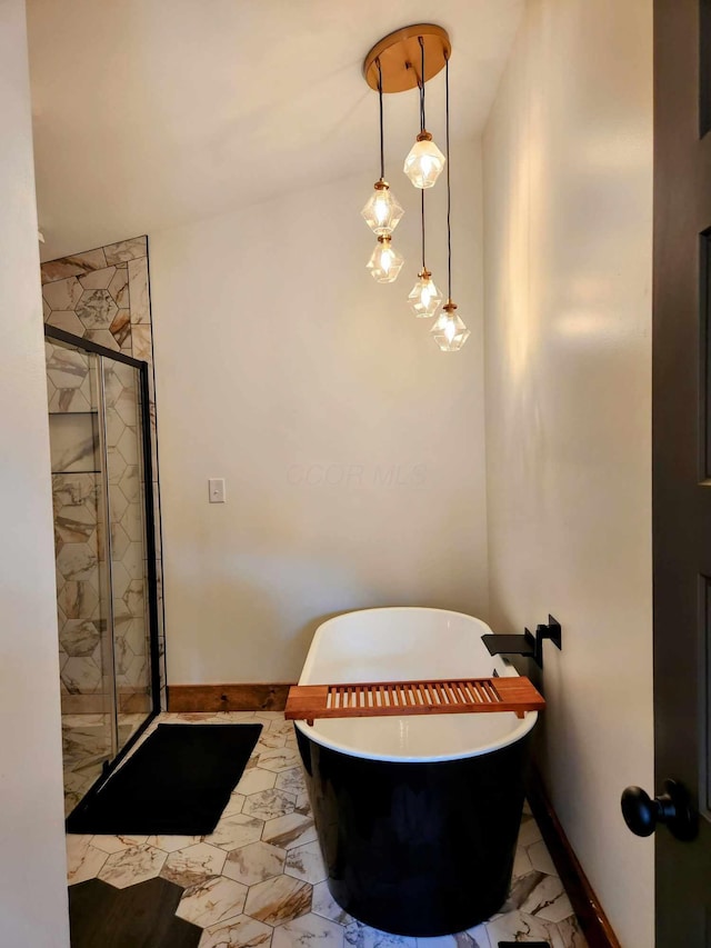 full bath with a stall shower, marble finish floor, a freestanding tub, and baseboards