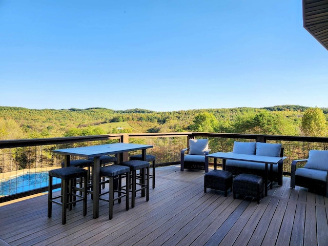 wooden terrace with an outdoor living space and a view of trees