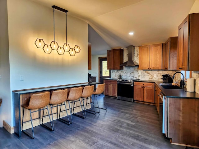 kitchen featuring dark countertops, stainless steel electric stove, vaulted ceiling, wall chimney range hood, and a sink