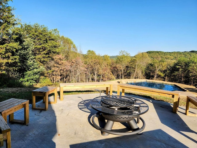 view of patio / terrace featuring a wooded view and an outdoor pool