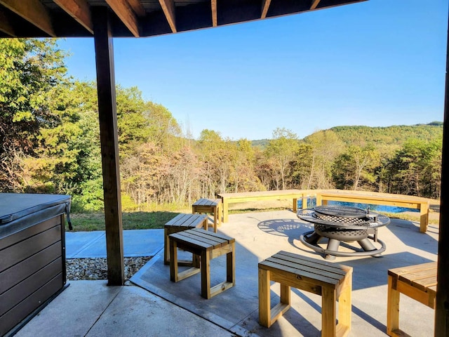 view of patio with a forest view and a hot tub