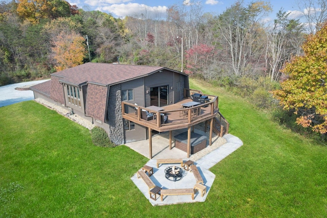 back of property featuring an outdoor fire pit, a lawn, a wooden deck, a patio area, and a wooded view