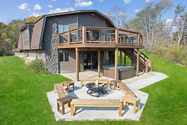 back of house featuring an outdoor fire pit, a hot tub, a lawn, a patio, and a deck