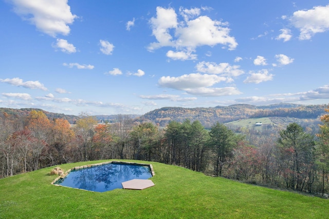 view of swimming pool featuring a mountain view, a view of trees, and a yard