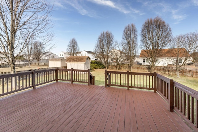 wooden deck featuring a storage shed, a lawn, an outdoor structure, and a fenced backyard