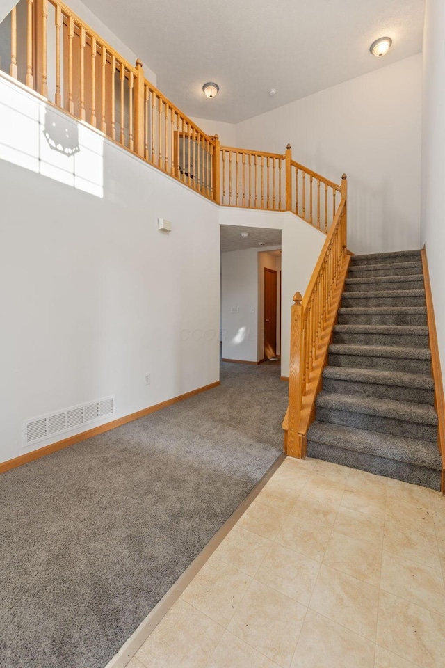 interior space featuring stairway, light carpet, visible vents, and baseboards