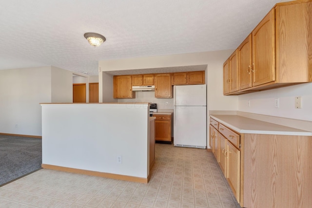 kitchen featuring baseboards, freestanding refrigerator, light countertops, a textured ceiling, and under cabinet range hood