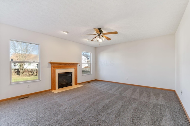 unfurnished living room with carpet, a fireplace with flush hearth, visible vents, and baseboards