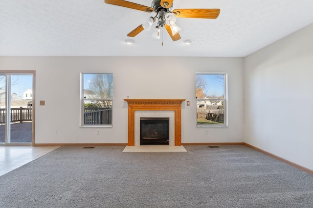 unfurnished living room featuring a textured ceiling, carpet, a fireplace with flush hearth, and baseboards