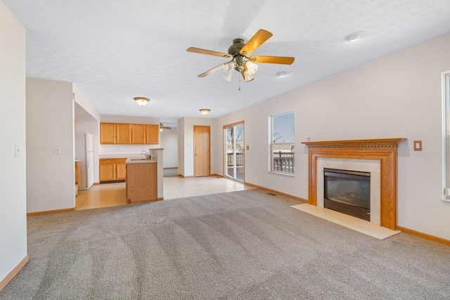 unfurnished living room featuring a fireplace with flush hearth, light carpet, a textured ceiling, and baseboards