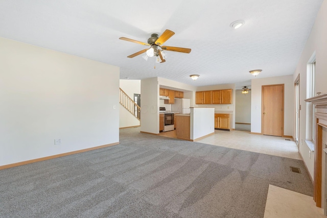 unfurnished living room featuring visible vents, stairway, light carpet, ceiling fan, and baseboards