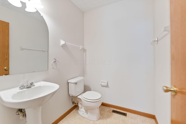 half bathroom with toilet, tile patterned floors, visible vents, and baseboards