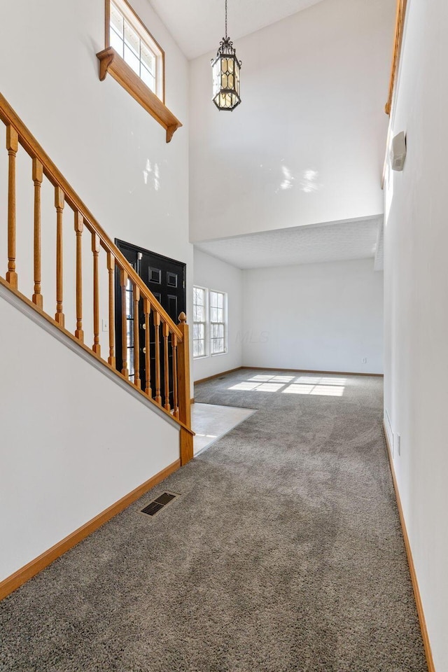 entrance foyer featuring carpet floors, visible vents, baseboards, and stairs