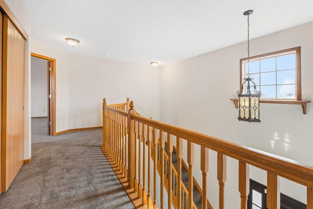 hall with carpet floors, baseboards, and an upstairs landing