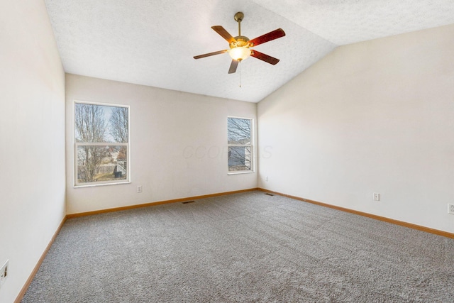 carpeted empty room with lofted ceiling, a textured ceiling, and baseboards