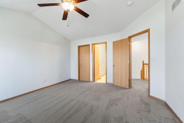 unfurnished bedroom with light carpet, baseboards, visible vents, and vaulted ceiling