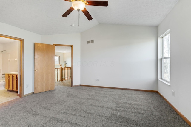 unfurnished bedroom with vaulted ceiling, light carpet, visible vents, and baseboards