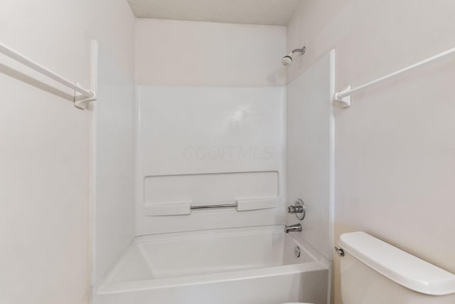 bathroom with toilet, bathtub / shower combination, and a textured ceiling