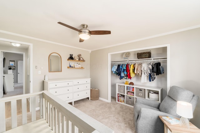 bedroom featuring ornamental molding, a closet, a nursery area, baseboards, and light colored carpet