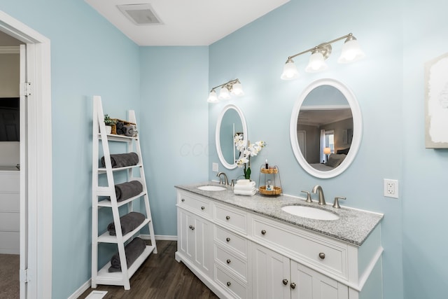 full bathroom with double vanity, visible vents, wood finished floors, and a sink