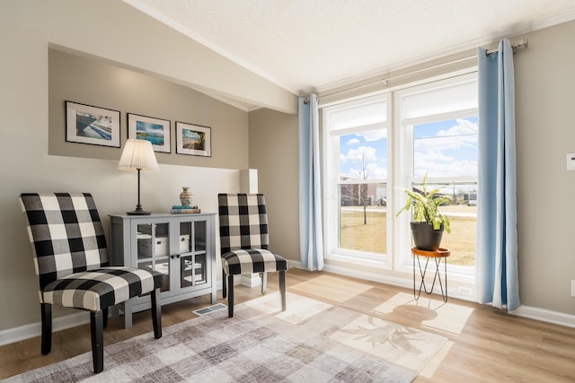 sitting room featuring vaulted ceiling, wood finished floors, baseboards, and a textured ceiling