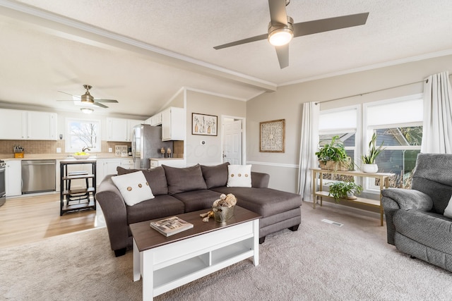 living area with lofted ceiling, ceiling fan, ornamental molding, a textured ceiling, and light carpet