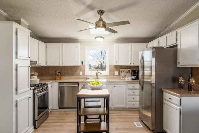 kitchen featuring visible vents, appliances with stainless steel finishes, a sink, and ornamental molding