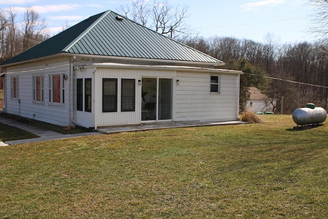 back of property with metal roof and a lawn