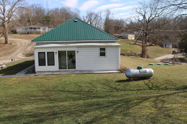 back of property with an outbuilding, metal roof, and a lawn