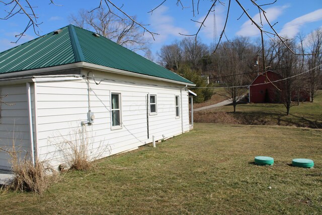 view of property exterior with an outbuilding, metal roof, a lawn, and a barn